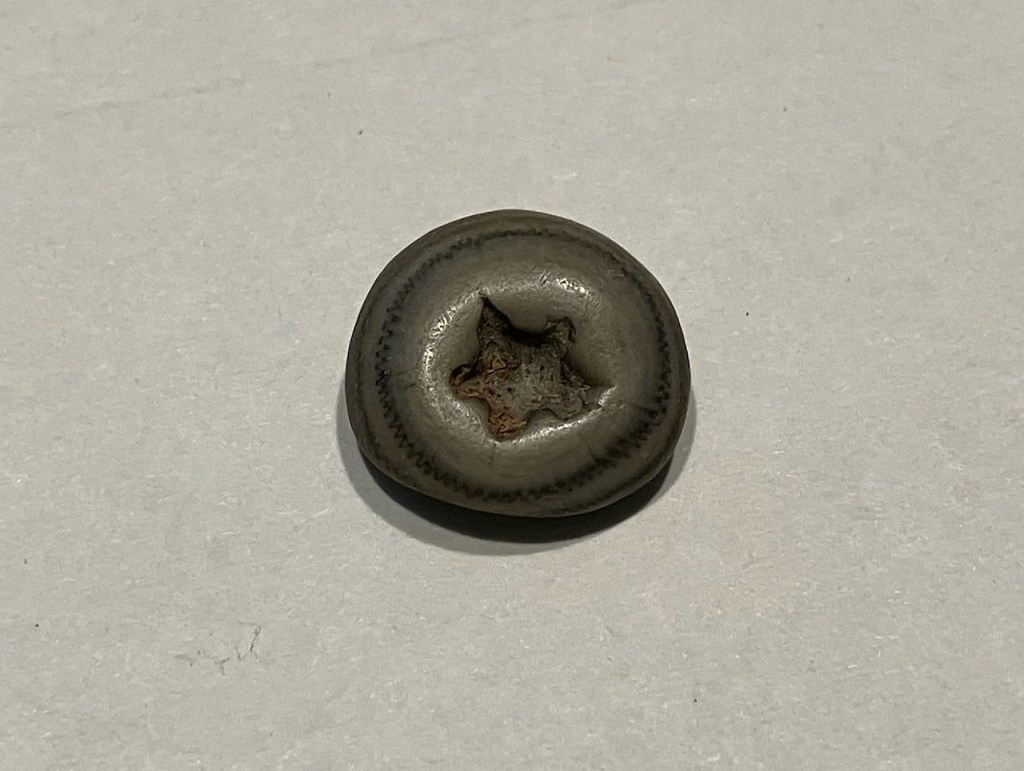 small gray round stone with star shaped hole in center